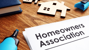 Homeowners Association document on a wooden desk with a blue highlighter and miniature house models, representing HOA governance and policies.