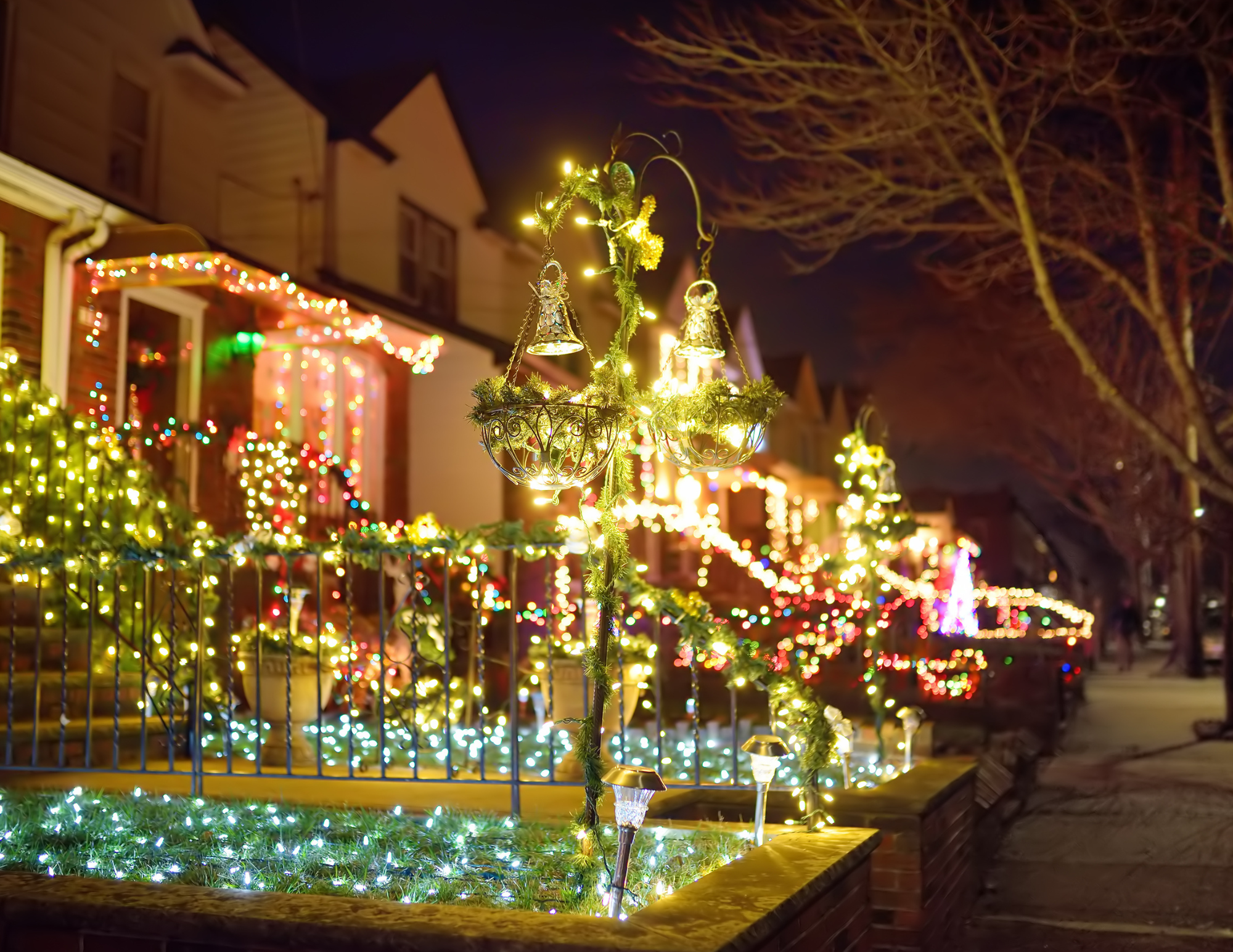 Neighborhood houses glowing with festive Christmas light displays at night.