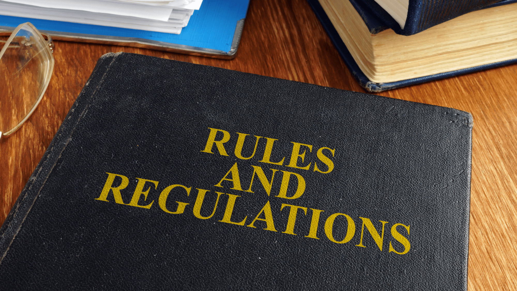 A black book labeled 'Rules and Regulations' placed on a desk with legal documents, symbolizing HOA guidelines and community governance.