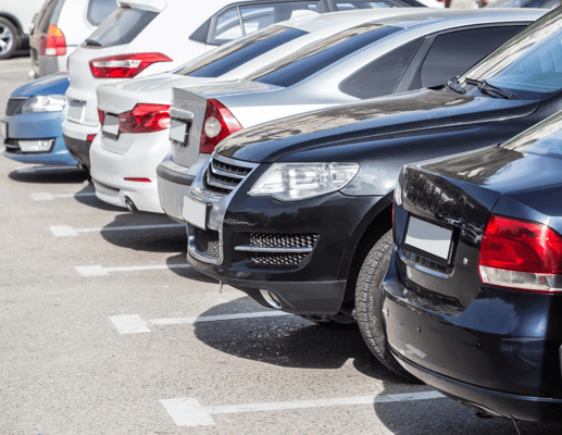 Row of cars parked neatly in a community parking lot.