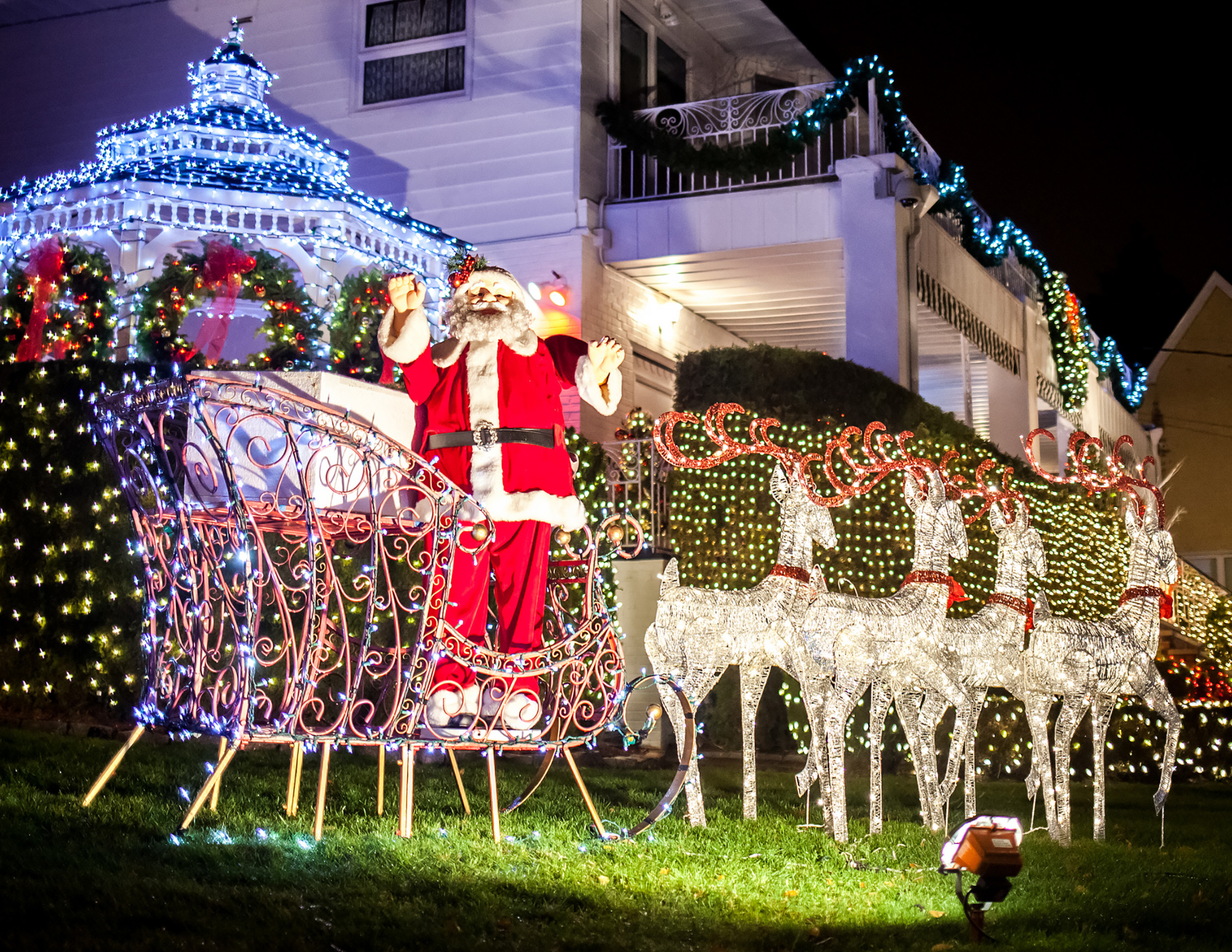 Front yard illuminated with Christmas lights, including a Santa sleigh and reindeer display.