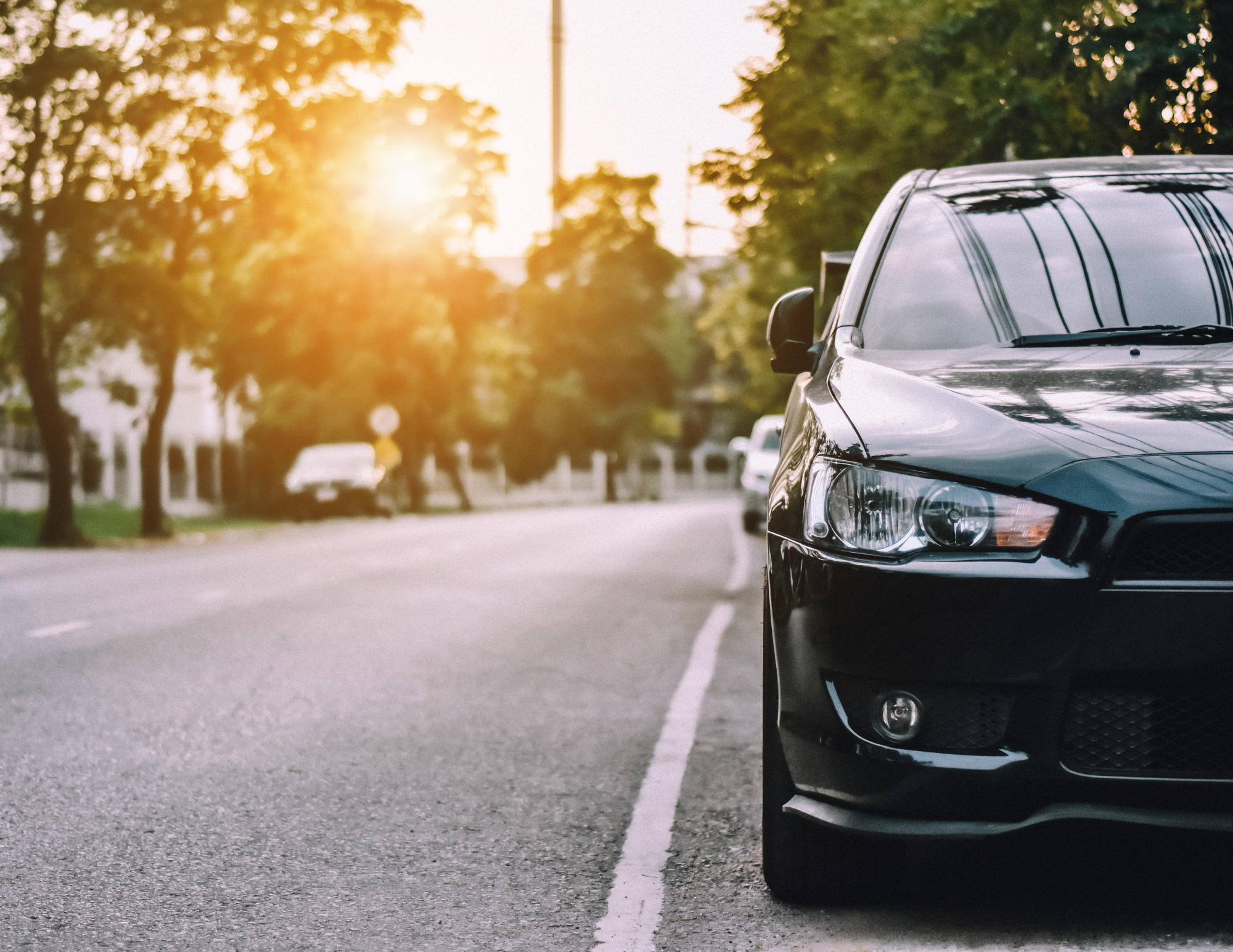 Car parked on a quiet residential street during sunset.