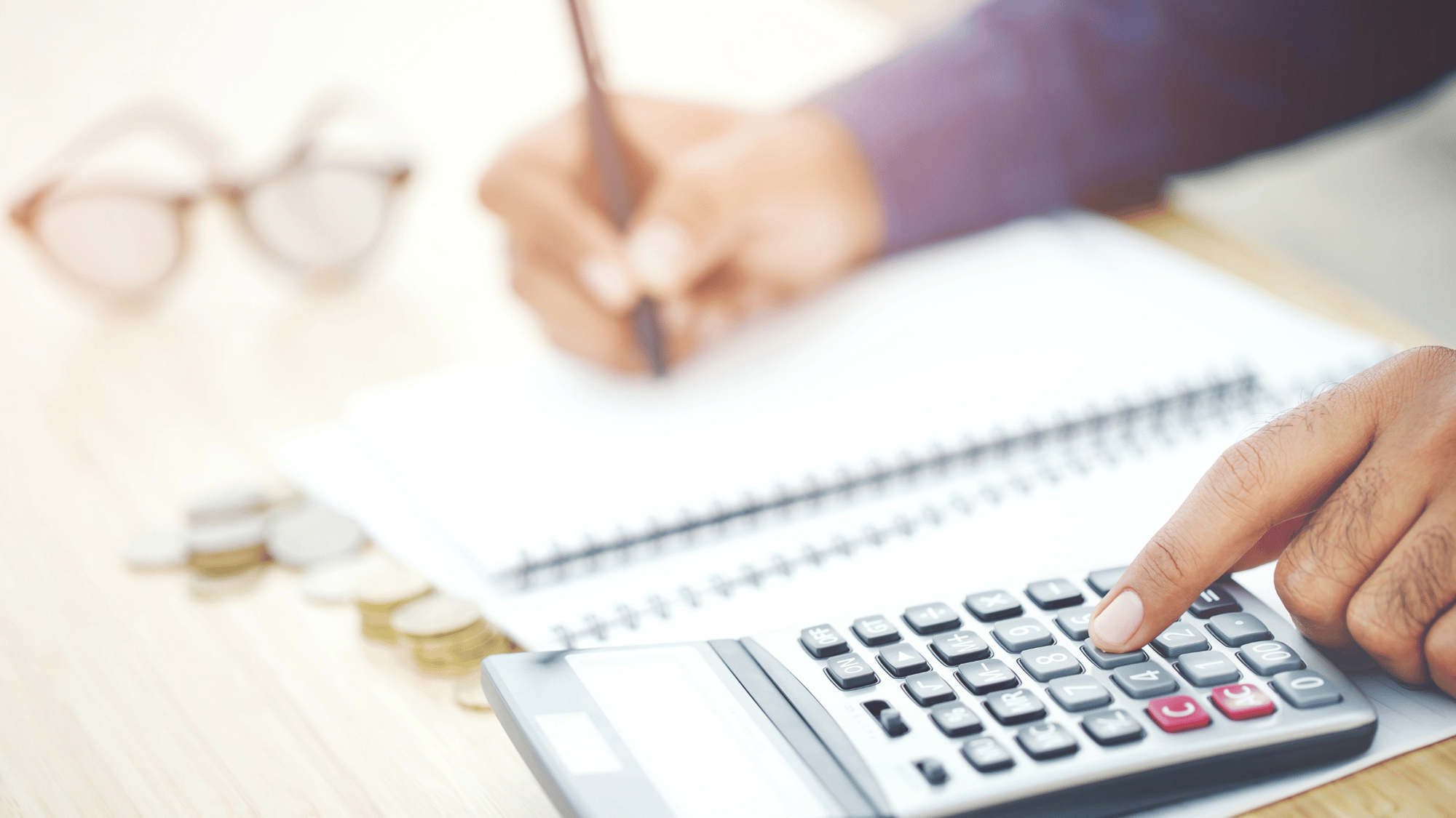 Close-up of a person using a calculator and taking notes, representing HOA financial management and budgeting.