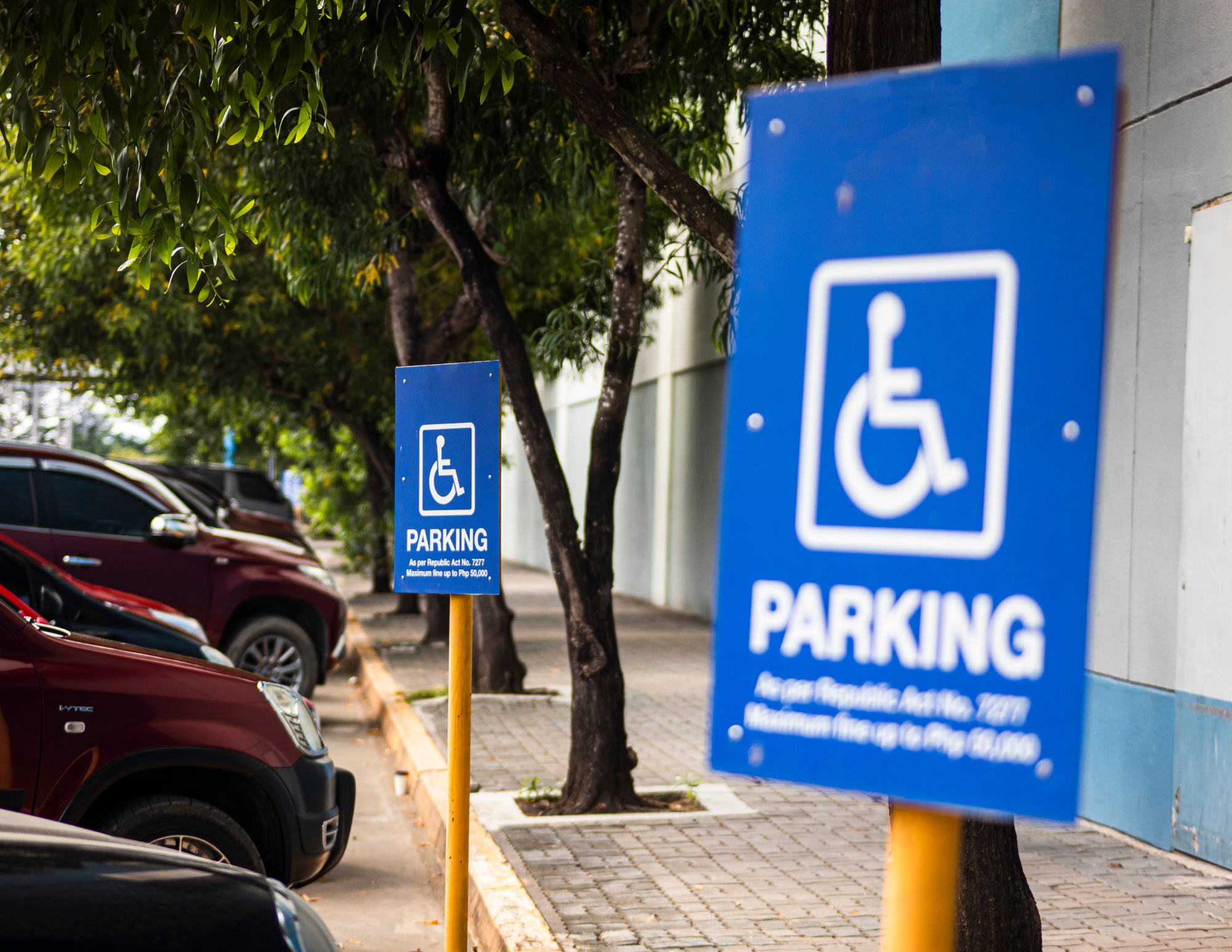 Handicap parking signs in a community parking lot with parked vehicles.