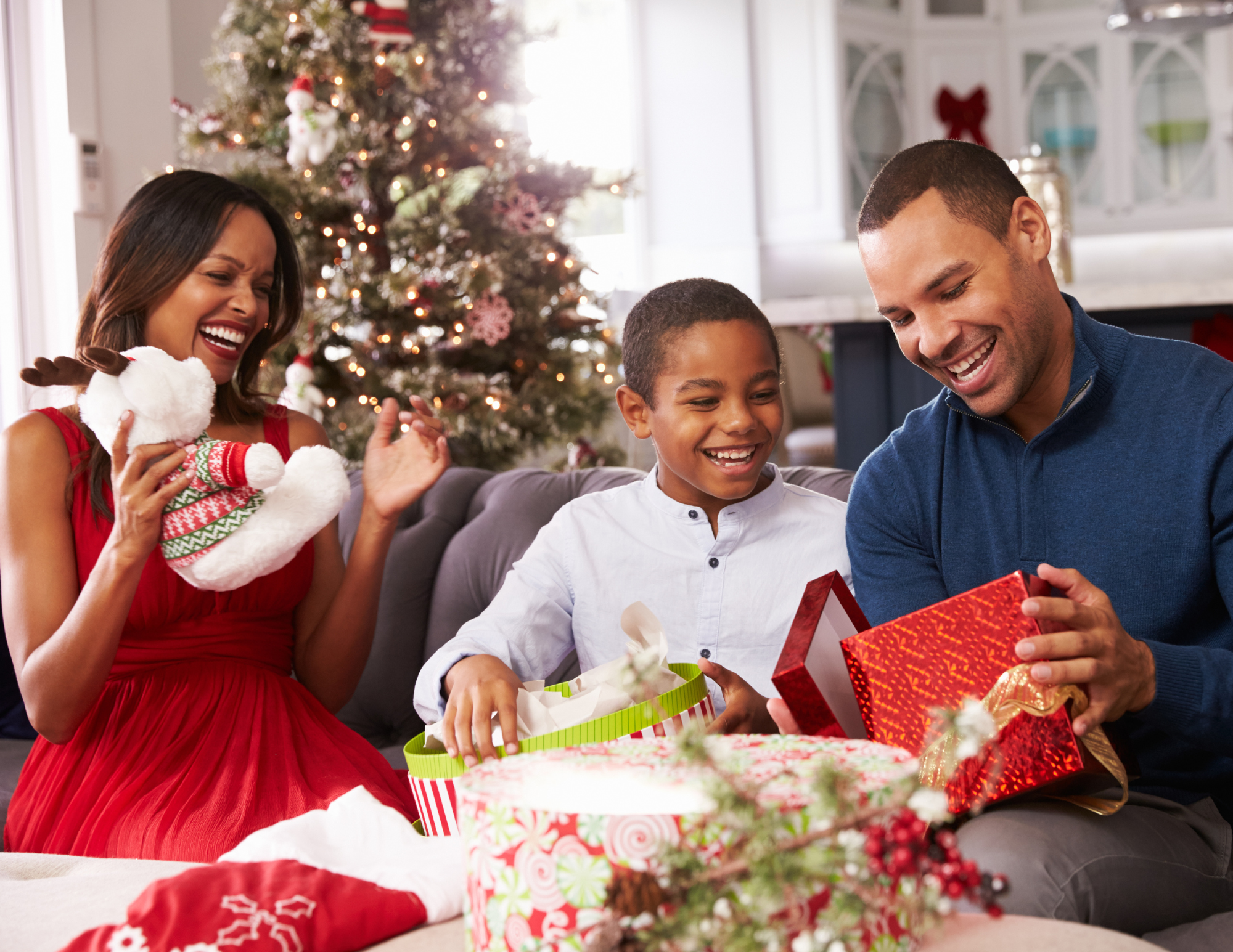 Family exchanging gifts near a beautifully decorated Christmas tree in their home.